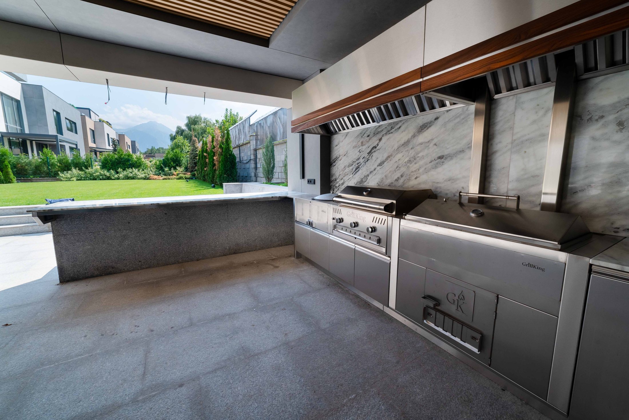 Inside a GrillKing outdoor kitchen: the stainless line, the lawn and the mountains beyond