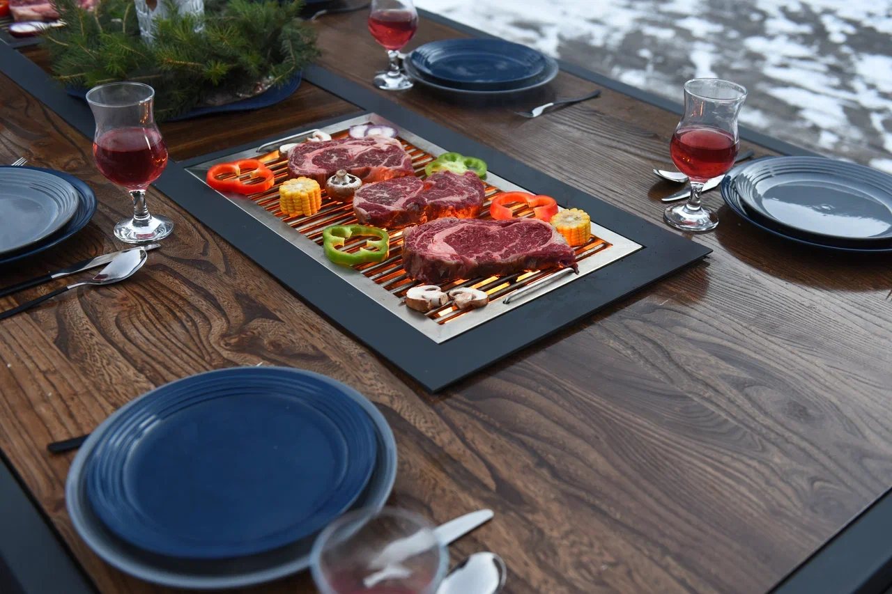 King's Table: steaks, peppers, corn and mushrooms on the grate in the tabletop