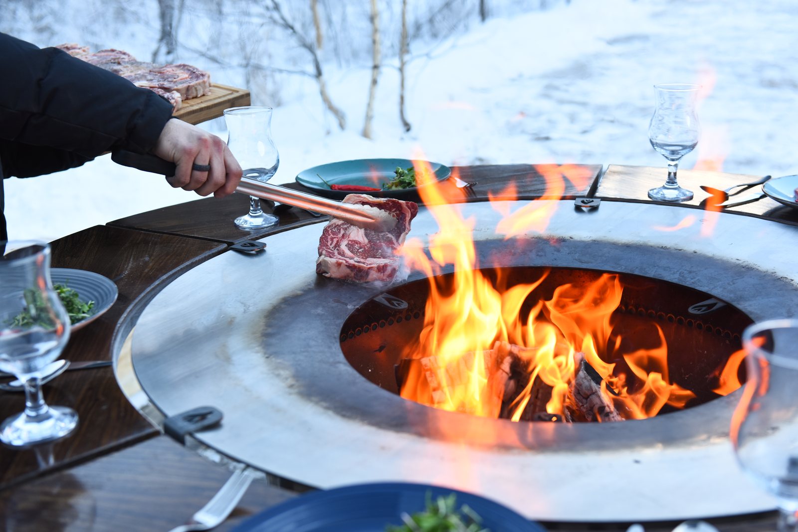 Стейк кладут щипцами на стальное кольцо Royal Bonfire