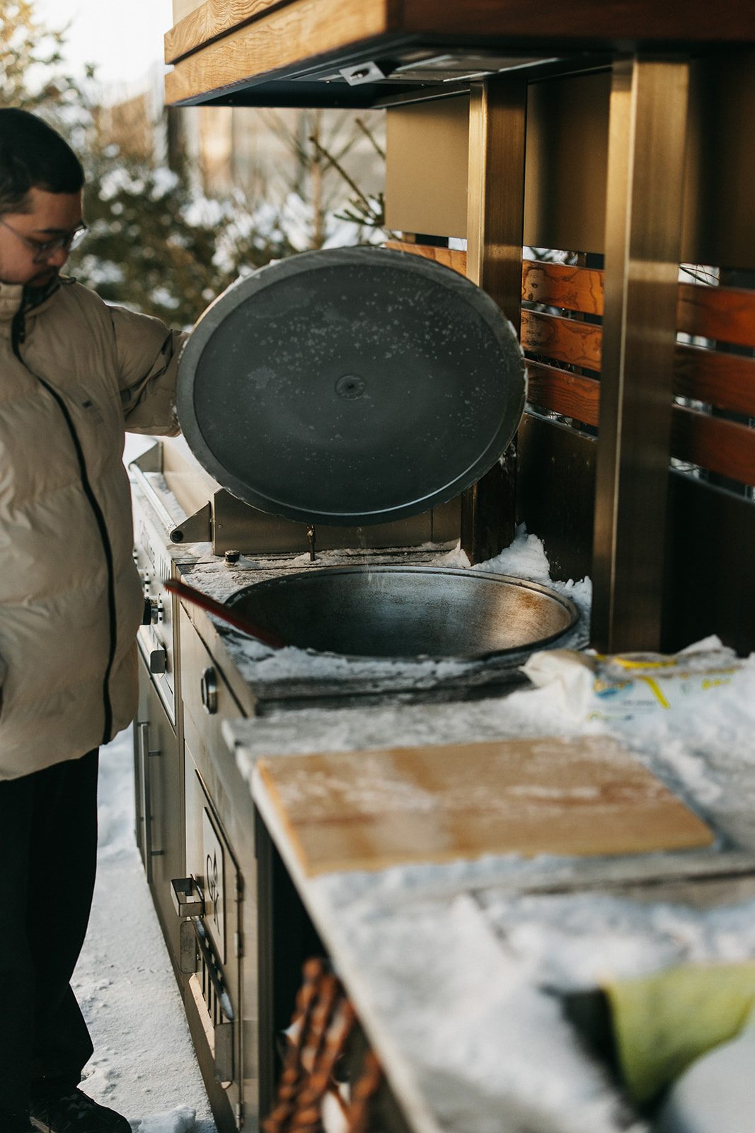 Повар готовит на сковороде GrillKing на уличной кухне зимой